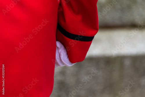 An RCMP officer stands at attention on parade wearing a red serge uniform. The jacket and sleeve is vibrant red color with a small black band around the wrist. The officer is wearing white gloves.  © Dolores  Harvey