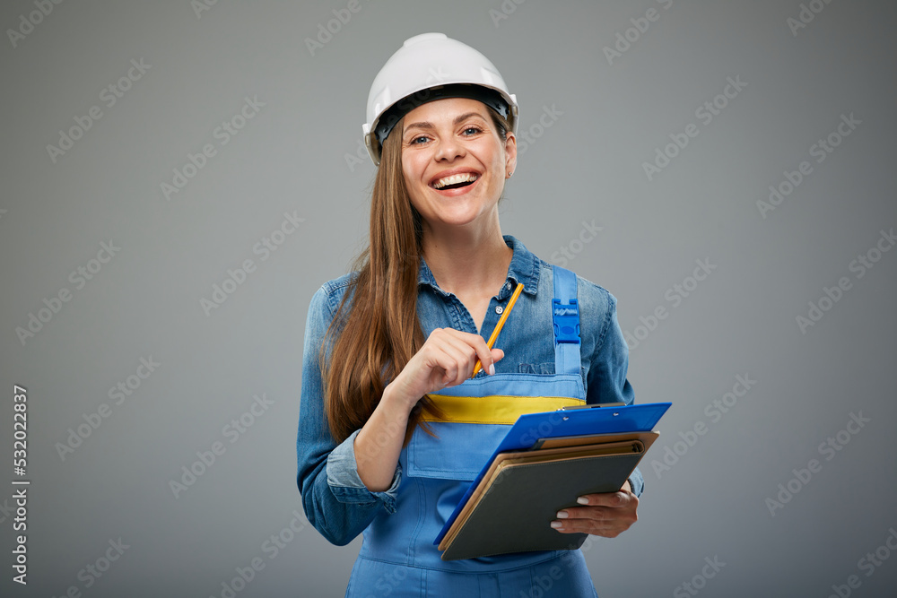 Woman engineer student in white helmet and overall writes on clipboard. Isolated female builder portrait. Woman engineer student in white helmet and overall writes on clipboard. Isolated female builder portrait.