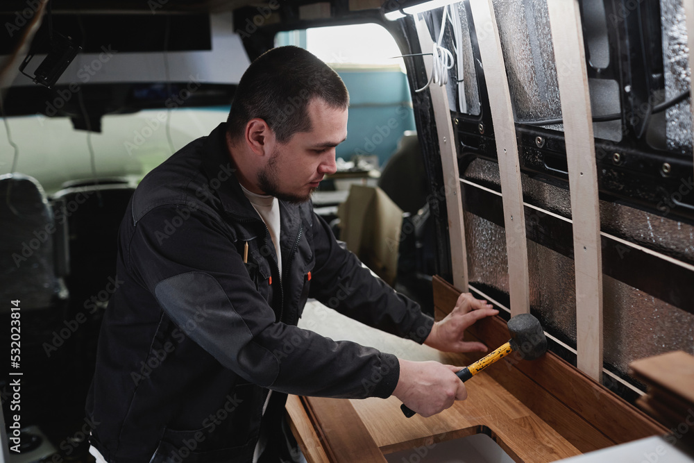 © Seventyfour - Side view portrait of young man building camper van and installing furniture in kitchen area © Seventyfour - Side view portrait of young man building camper van and installing furniture in kitchen area