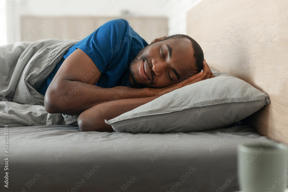 Happy African Man Sleeping Lying In Cozy Bed In Bedroom Happy African Man Sleeping Lying In Cozy Bed In Bedroom