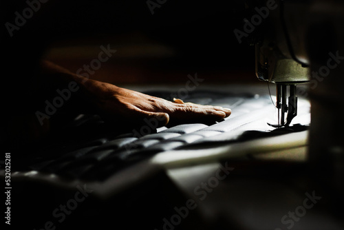Fotografia Close up of person sewing car upholstery detail with industrial sewing machine,