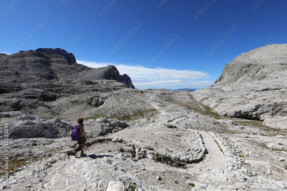 Young woman walks on the trail of the Dolomites in the European Alps called Pale Group  in Italy