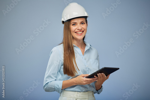Smiling woman engineer in safety helmet holding tablet. Isolated female portrait.