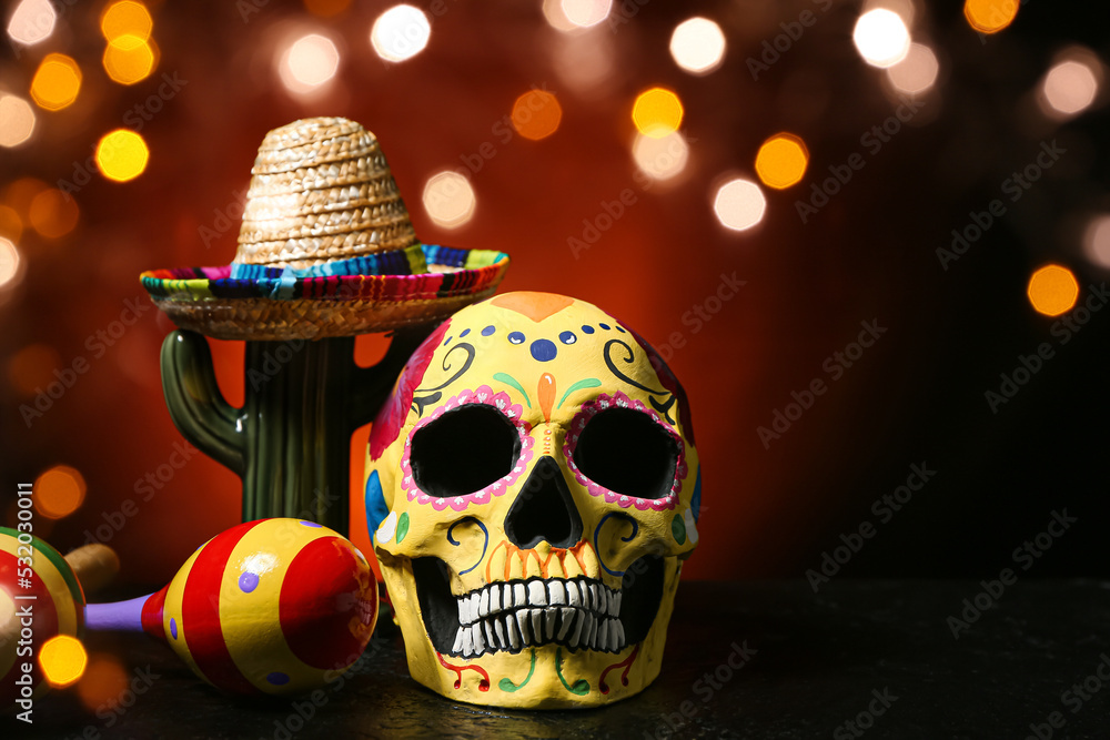 Painted human skull for Mexico's Day of the Dead (El Dia de Muertos), maracas, cactus and sombrero on dark background - obrazy, fototapety, plakaty 