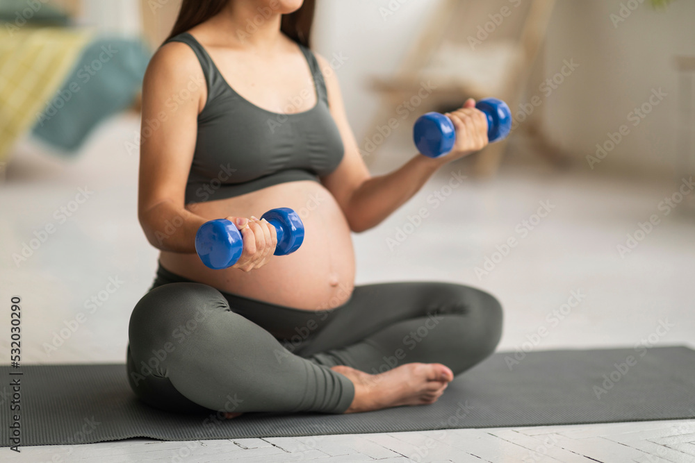 Unrecognizable Young Pregnant Woman In Activewear Training With Dumbbells At Home Unrecognizable Young Pregnant Woman In Activewear Training With Dumbbells At Home