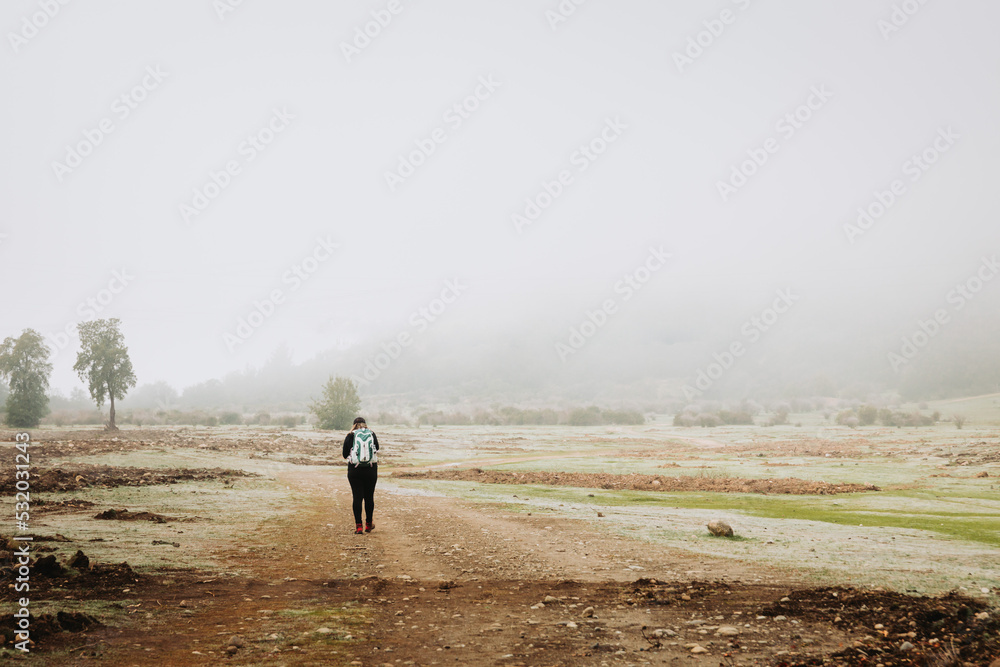 Young latin plus size woman with backpack on, climbing a hill and hiking in a beautiful landscape. Vertical Young latin plus size woman with backpack on, climbing a hill and hiking in a beautiful landscape. Vertical