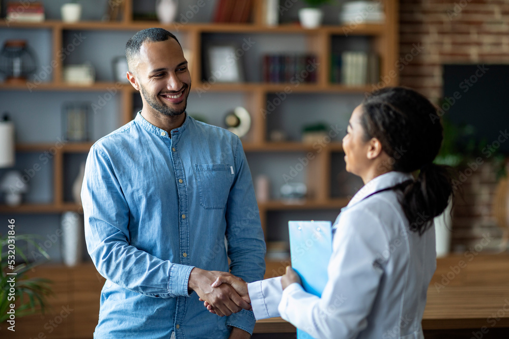 Obraz premium Cheerful african american woman doctor greeting male patient