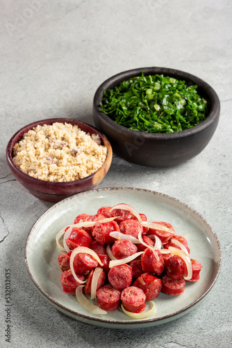 Sliced sausage with onion, green cabbage and farofa.