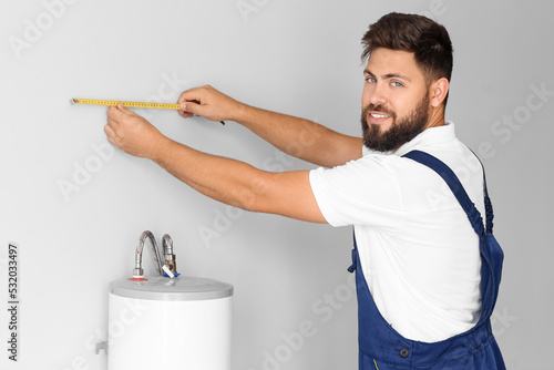 Male plumber measuring wall...