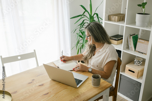 Caucasian woman sitting and writing in notebook at home