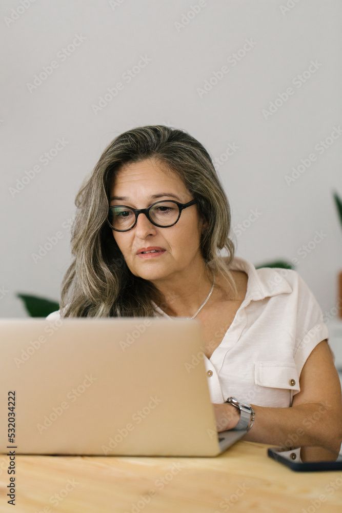 Focused mature woman working online via laptop Focused mature woman working online via laptop
