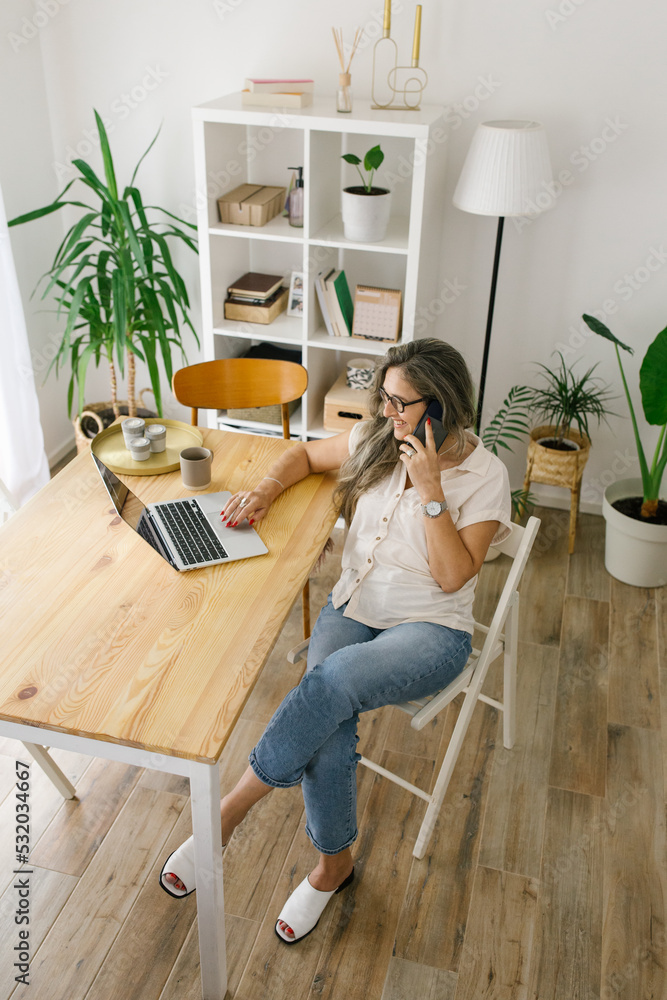 Happy woman working from home and talking on the phone Happy woman working from home and talking on the phone