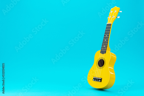 Perspective photo of ukulele with copy space. Yellow colored wooden ukulele guitar on the turquoise blue background. photo