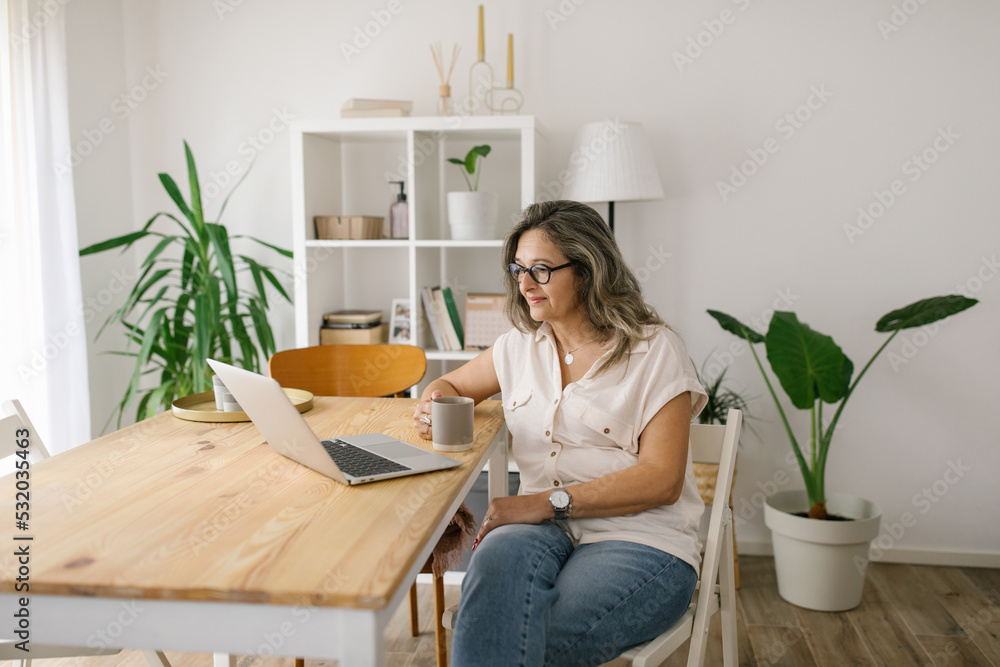 Woman sitting and reading from computer screen at home Woman sitting and reading from computer screen at home