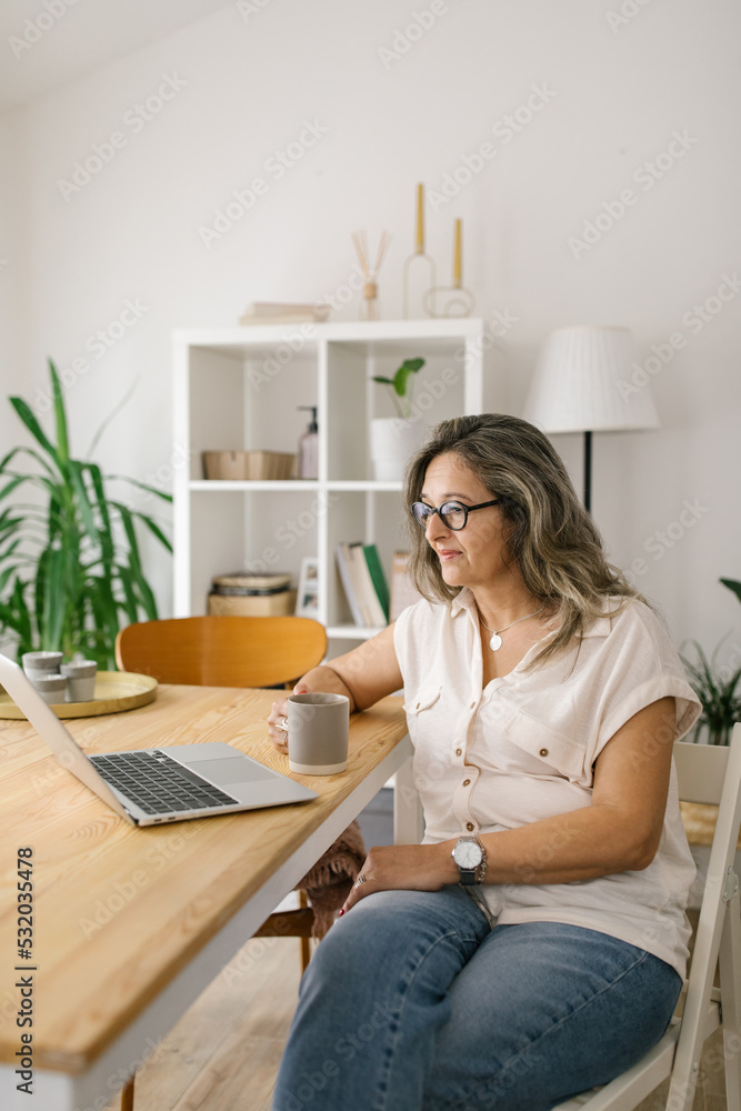 Woman sitting and reading from computer screen at home Woman sitting and reading from computer screen at home