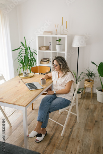 Woman sitting and reading from computer screen at home