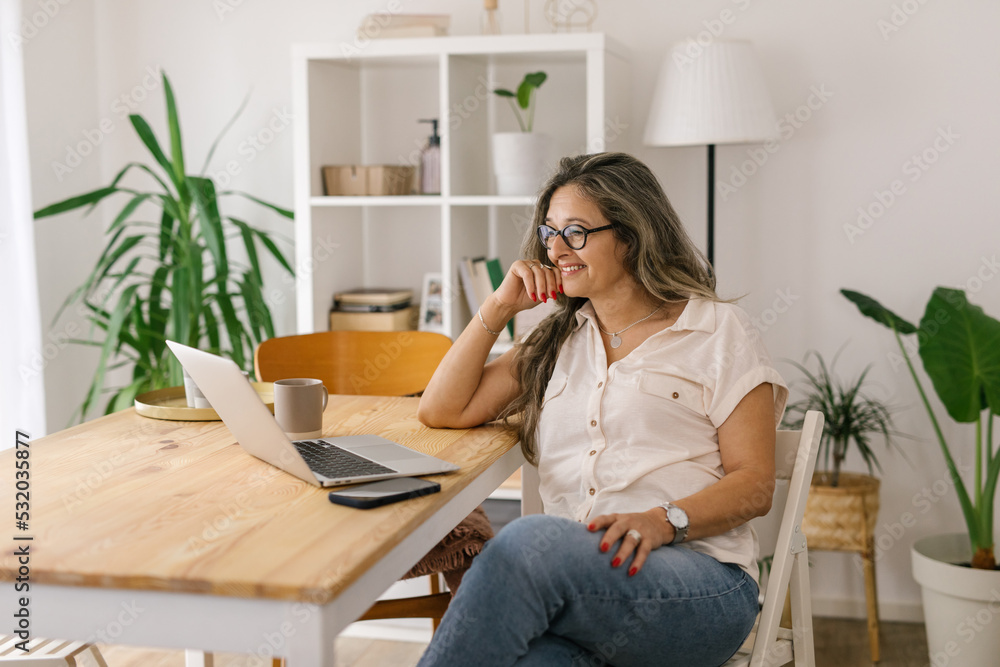 Smiling boomer woman face timing via laptop at home Smiling boomer woman face timing via laptop at home