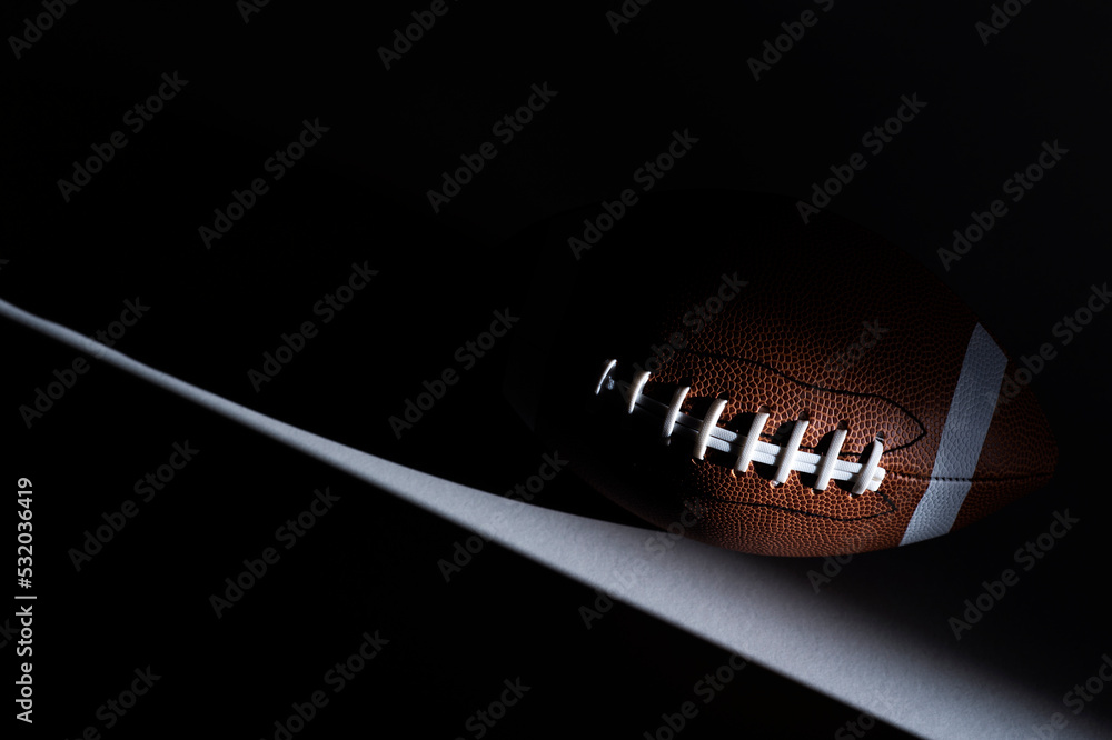 American football ball with natural lighting on dark background. Horizontal sport theme poster, greeting cards, headers, website and app - obrazy, fototapety, plakaty 