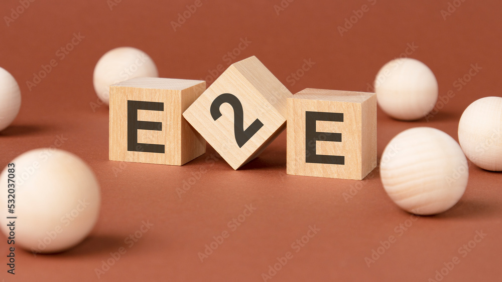 wooden cubes with word e2e on brown background. front view wooden cubes with word e2e on brown background. front view