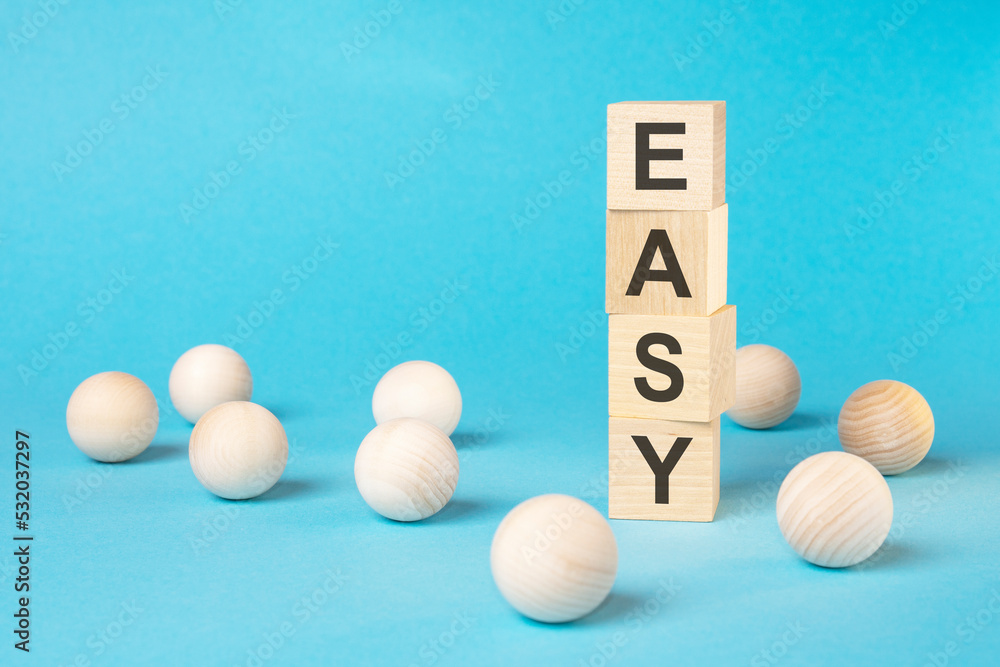 EASY - text on wooden block with bright blue background EASY - text on wooden block with bright blue background
