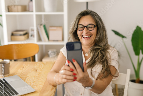 Happy woman video chatting via smartphone at home
