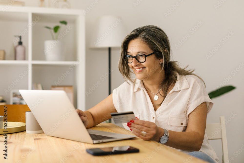 Happy boomer female shopping online via laptop at home Happy boomer female shopping online via laptop at home