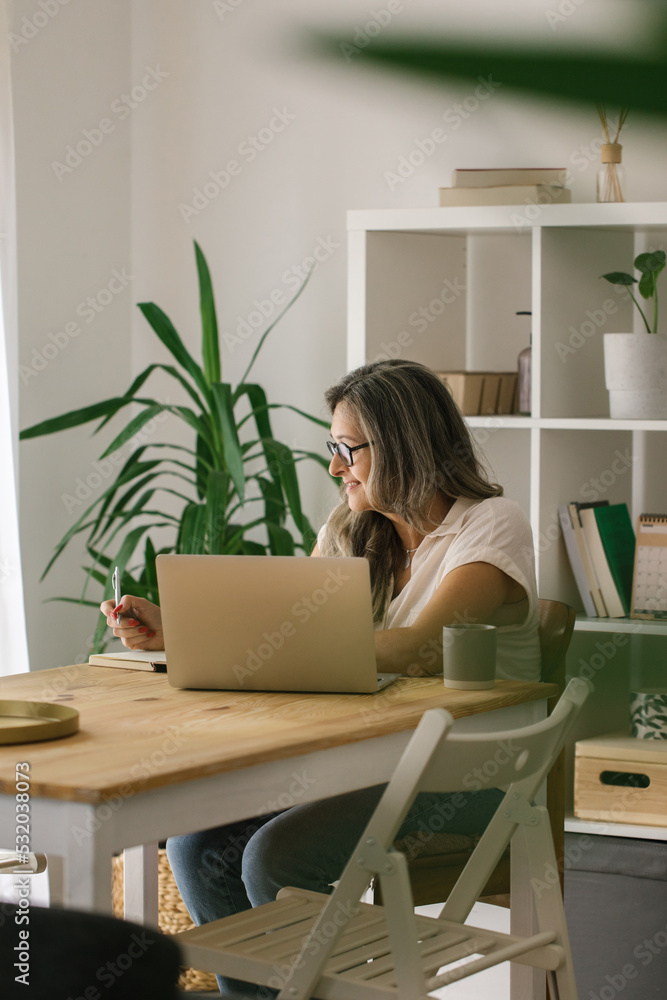 Mature woman woking online from home via laptop Mature woman woking online from home via laptop