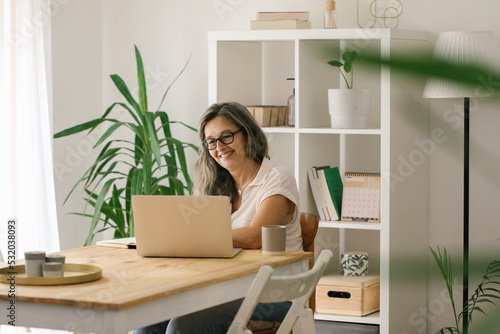 Mature happy woman woking online from home via laptop