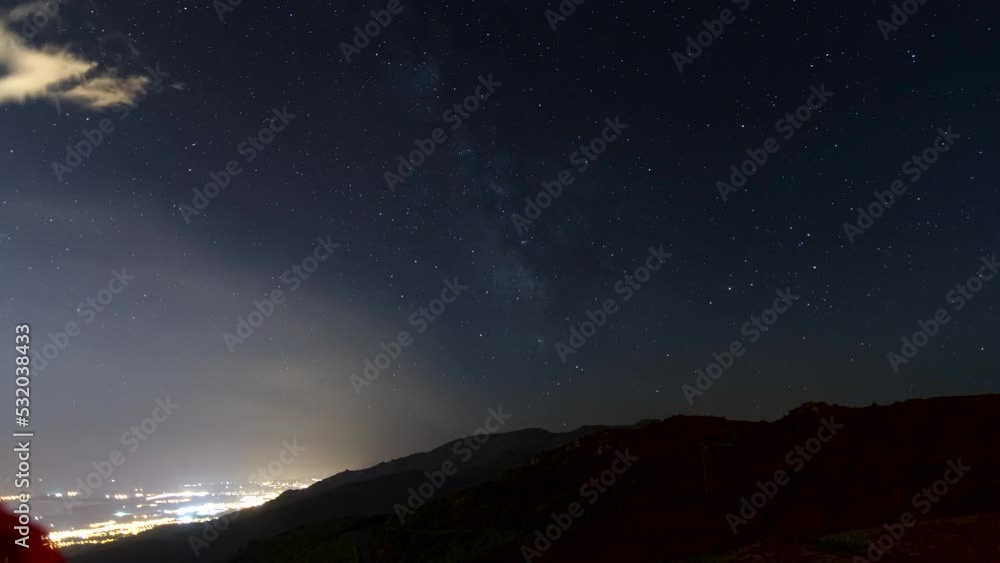 Night time lapse shot with milky way and stars and mountain Monte Canarinco near Bastia. Lights of a city Biguglia on bottom left Night time lapse shot with milky way and stars and mountain Monte Canarinco near Bastia. Lights of a city Biguglia on bottom left