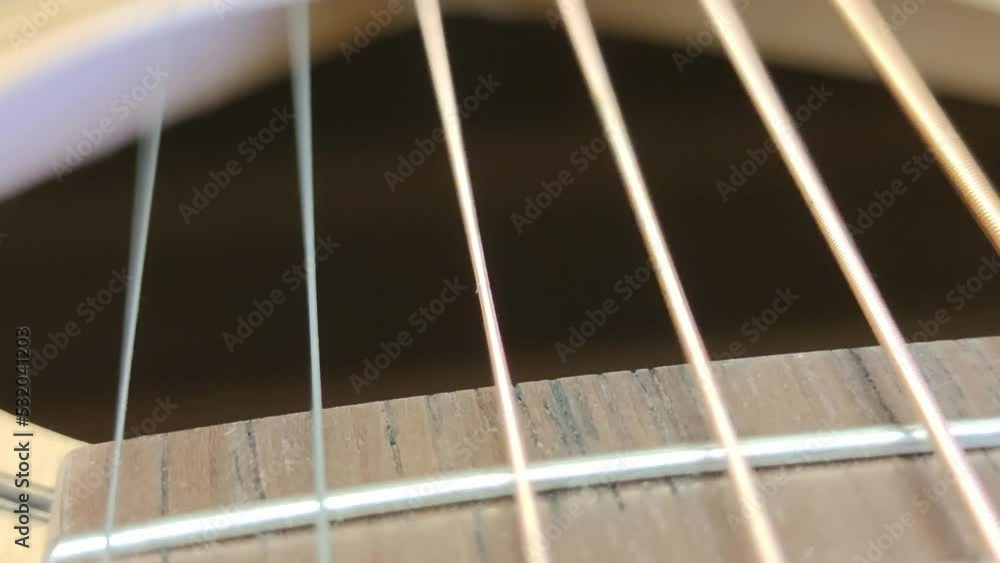 Guitar strings vibrate when touched. Close-up on metal strings. They have different thickness and different tone of sound. When touched, the strings begin to vibrate and make a sound. Guitar strings vibrate when touched. Close-up on metal strings. They have different thickness and different tone of sound. When touched, the strings begin to vibrate and make a sound.