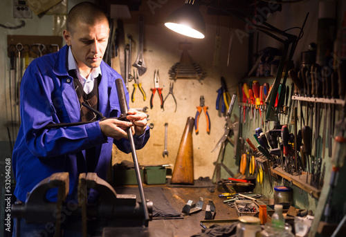 Portrait of qualified confident master of weapons working in workshop, repairing or renovating firearms .