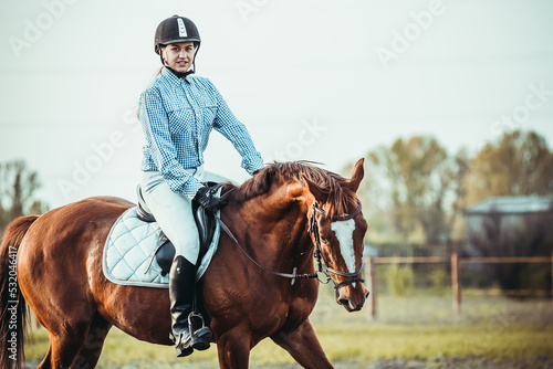 Young woman athlete rides a horse. Jumping training in the spring in the field. © sergo321