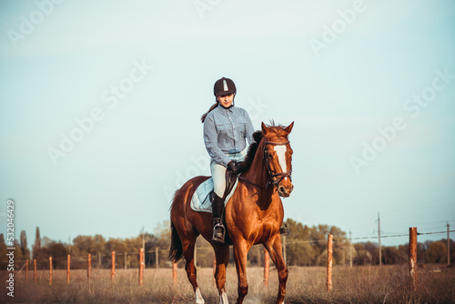 Young woman athlete rides a horse. Jumping training in the spring in the field.