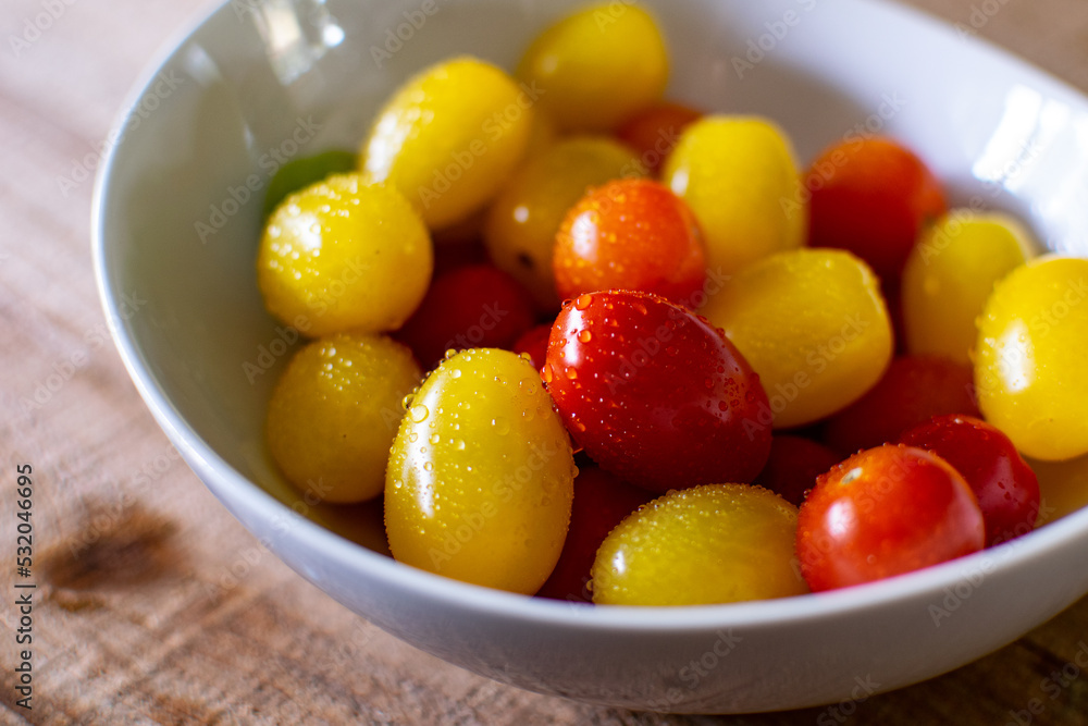 Cherry Tomatoes in Red, Yellow, Orange and Green. White Tomato Bowl on Dark Wood Table. Fresh Produce and Vegetables with Ripe, Small Tomatoes.