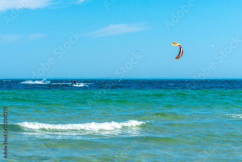 Kite surfer in the distance on turquoise waters of Baltic sea. Hel, Poland, Europe. Sport and recreation by the sea. Summer holiday.