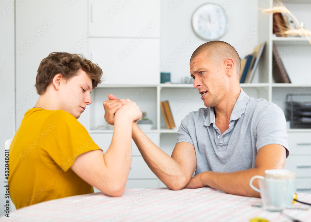 Obraz premium Father arm wrestling his son. They're happy and havung fun.