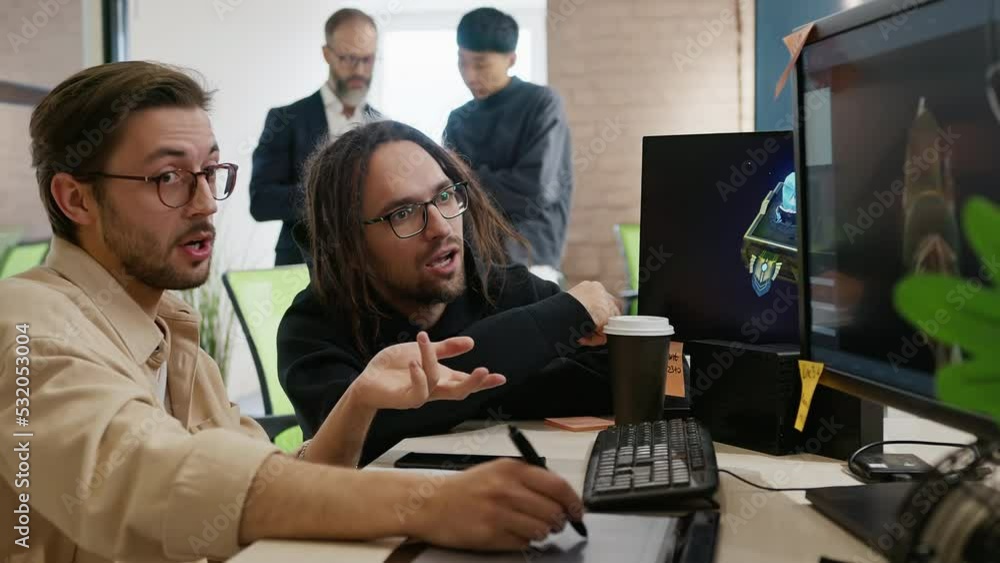 Artists employees of the company for 3D development of games and applications for the computer are actively and emotionally discussing the project while sitting in front of the monitor in the studio. Artists employees of the company for 3D development of games and applications for the computer are actively and emotionally discussing the project while sitting in front of the monitor in the studio.