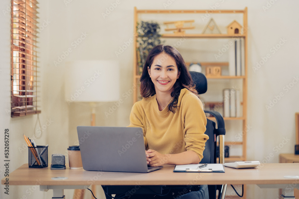 Portrait of a beautiful Asian woman looking at laptop screen while sitting at working desk in the office Portrait of a beautiful Asian woman looking at laptop screen while sitting at working desk in the office