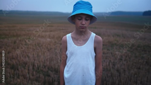Portrait of Refugee Boy in a hat Looks Compassionately At The Camera, Homeless Boy, Pain On Face, foggy weather in the evening, dynamic shot