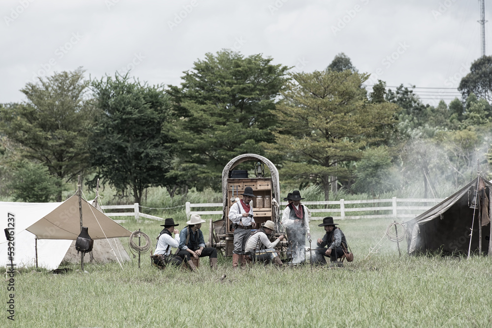 Obraz premium a group of people on a farm. group of cowboy camping in fields with wagon.
