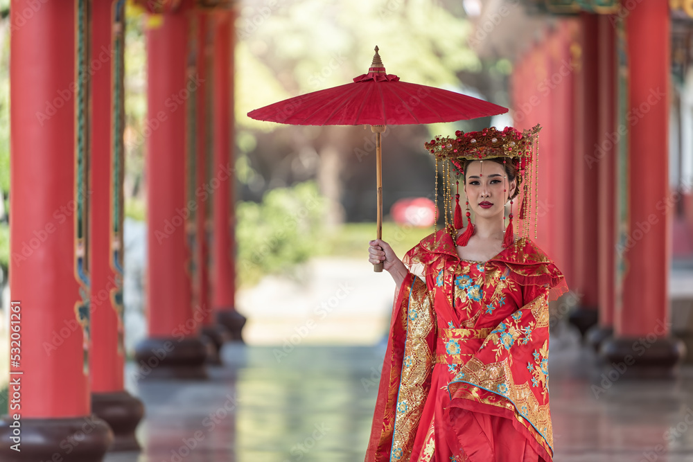 portrait of a woman. person in traditional costume. woman in traditional costume. Beautiful young woman in a bright red dress and a crown of Chinese Queen posing against the ancient door. 