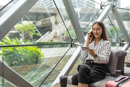 Young beautiful asian female businesswoman lady calling the bank credit card center to ask for credit line increase to make a online payment purchase while in a random cafe