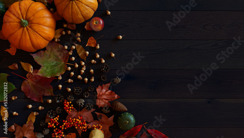 Seasonal Wallpaper, with Autumn Leaves, Pumpkins and Berries on a Dark wood Surface. Thanksgiving Concept with space for text.