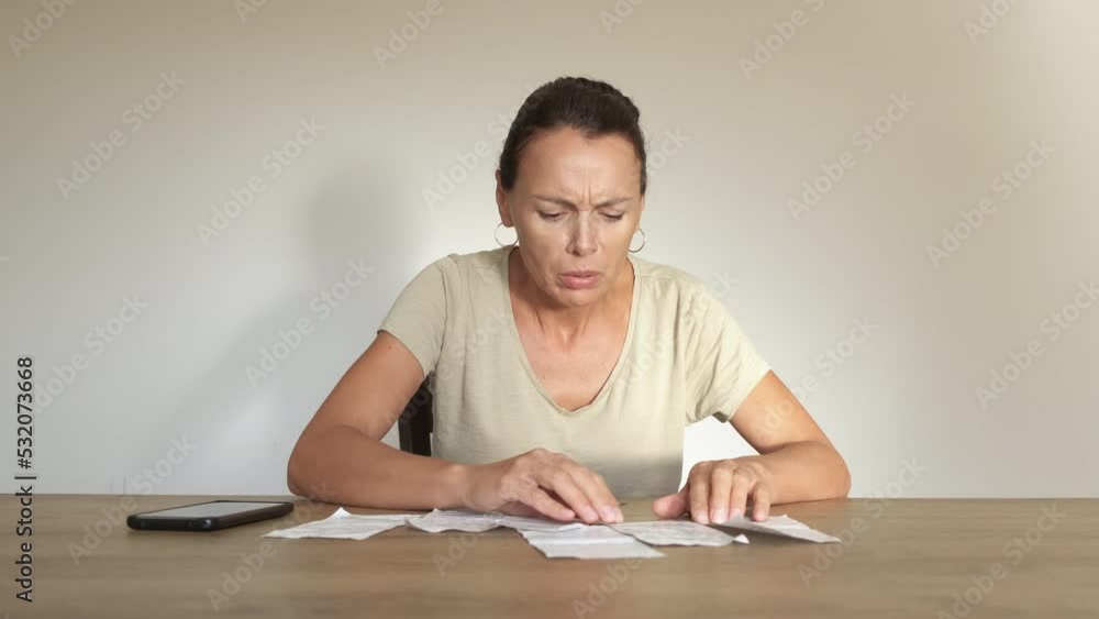 Female crisis bills for home appliances. An upset woman count electrical and gas bills on the table. A concept of expensive energy costs and inflation in Europe. Female crisis bills for home appliances. An upset woman count electrical and gas bills on the table. A concept of expensive energy costs and inflation in Europe.