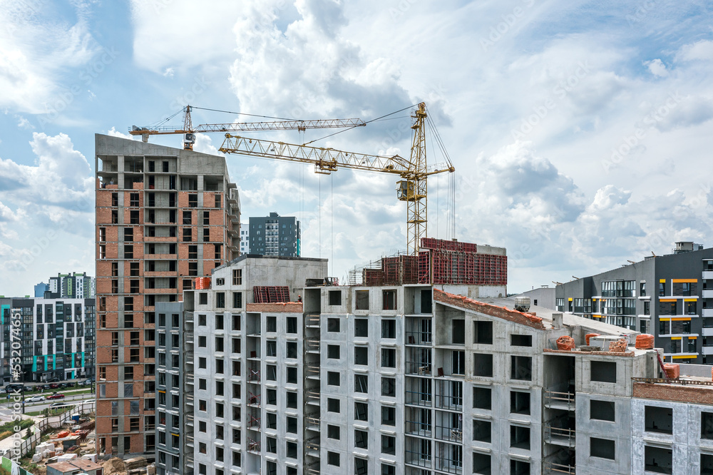 cranes and residential buildings under construction against blue sky background. city construction site. aerial photo. cranes and residential buildings under construction against blue sky background. city construction site. aerial photo.
