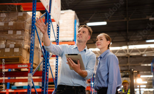 Warehouse manager talking and pointing towards shelf while checking product in warehouse, Logistic industry concept.