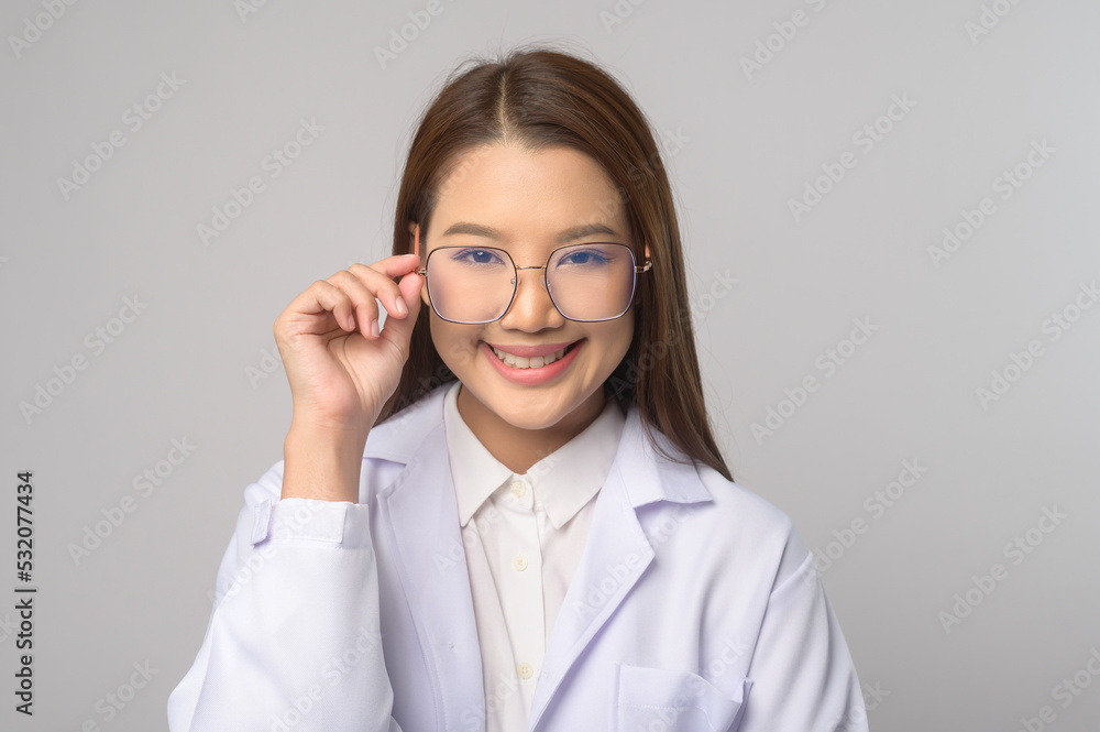 Young female ophthalmologist with glasses holding eye chart over blue background studio, healthcare concept.