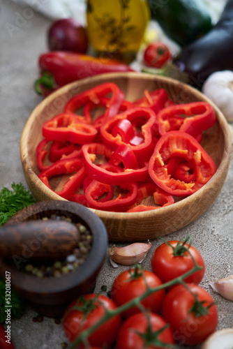 sliced red pepper in a wooden bowl and vegetables at domestic kitchen
