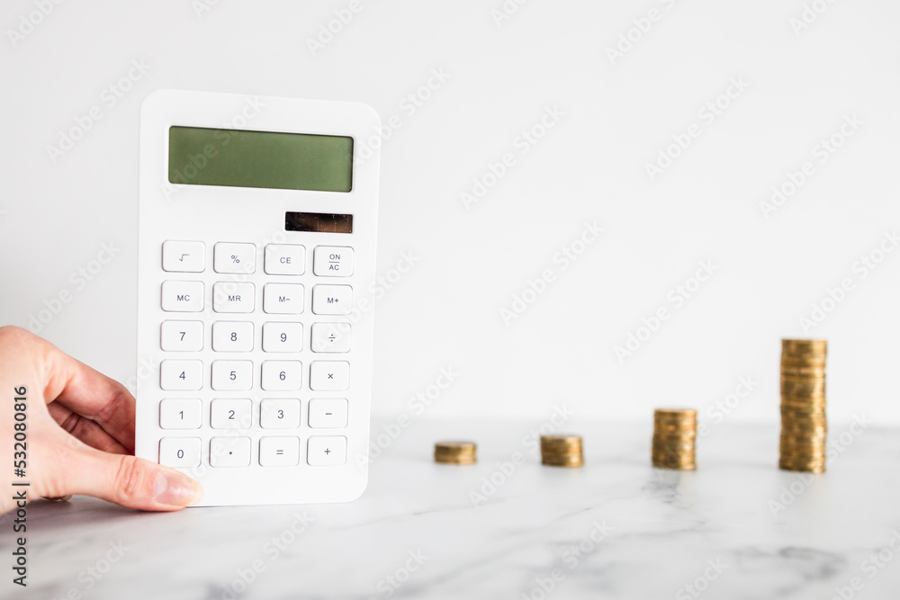 growing stacks of coins next to calculator representing increasingly expensive prices or savings and compound interests increasing, finance and money concept growing stacks of coins next to calculator representing increasingly expensive prices or savings and compound interests increasing, finance and money concept