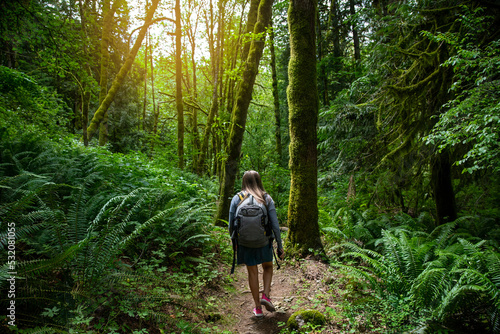 Solo Female Hiker walking through a lush wooded forest in the beautiful Pacific Northwest. Outdoor lifestyle photo